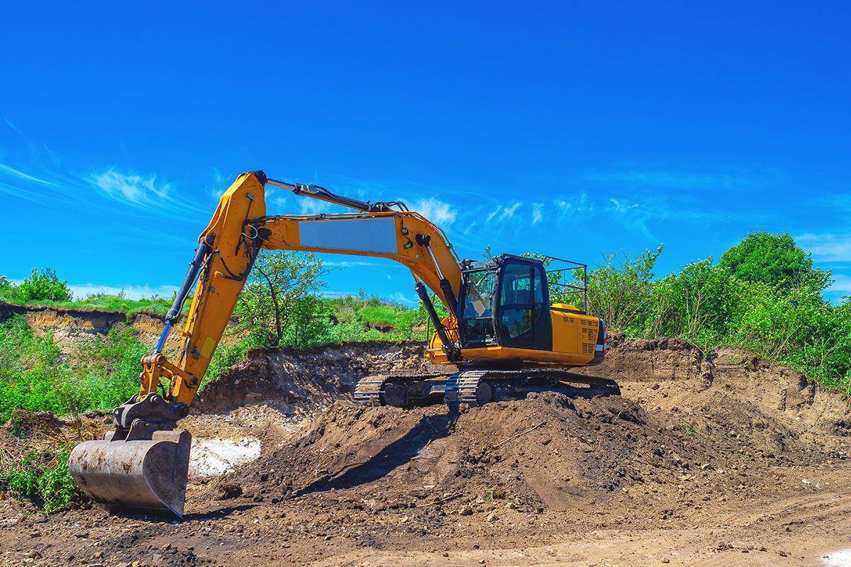 A yellow and black excavator on top of dirt.